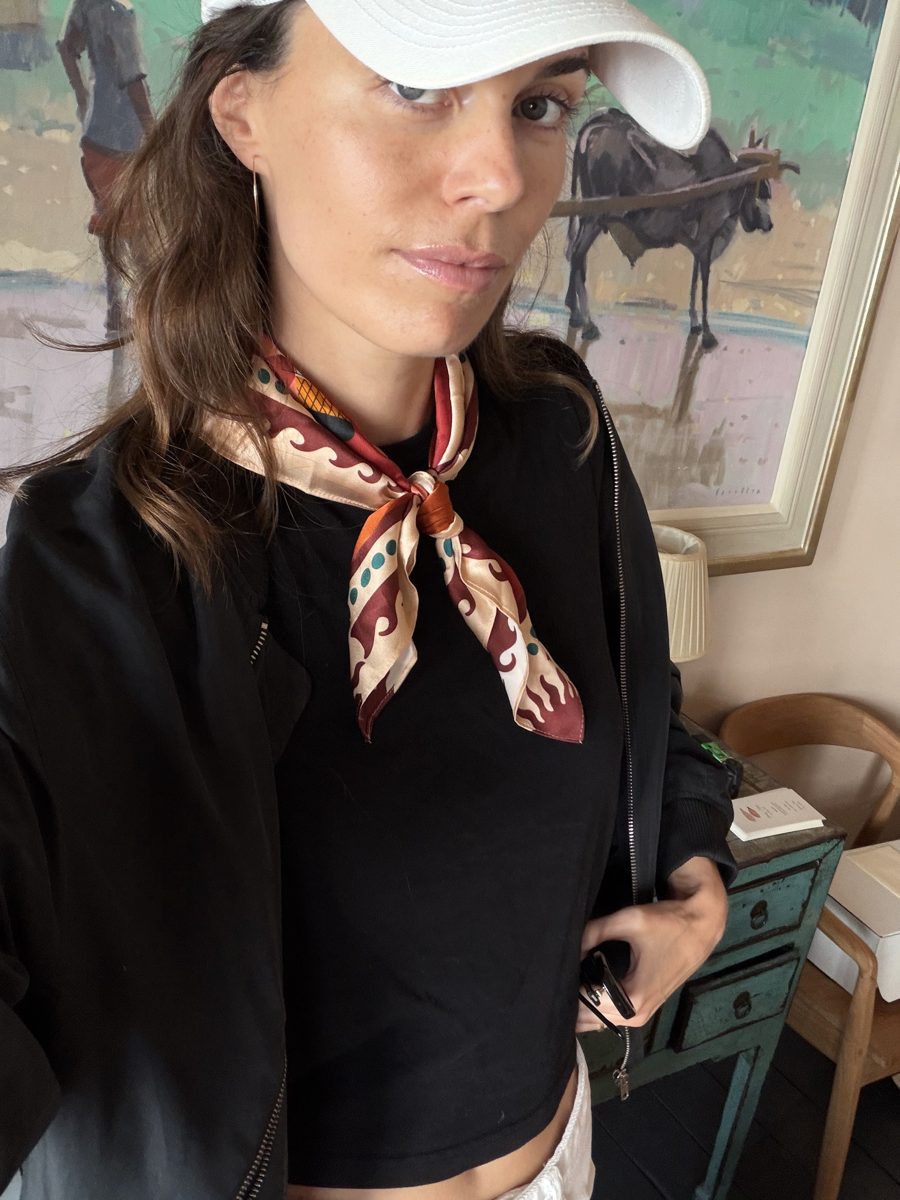 A guest in a cap wearing the scarf knotted at her neck